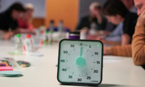 Mehanička štoperica na stolu sa zamagljenim ljudima u pozadini